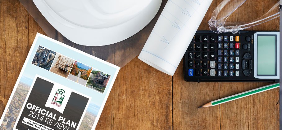 Official plan document on table with hard hat and other building tools