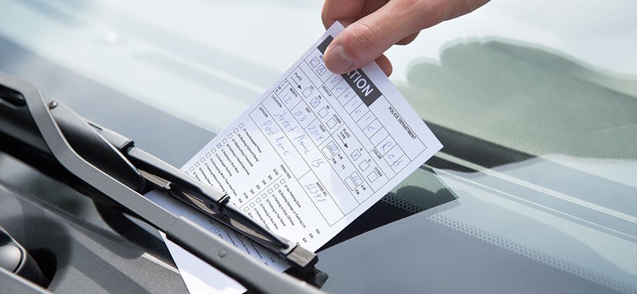 Parking ticket tucked under windshield wiper on car