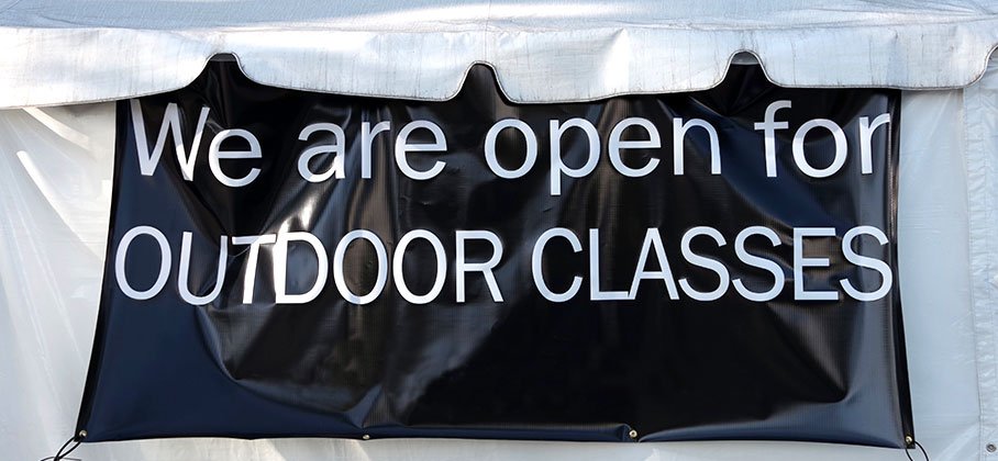 Tent with an exterior banner that says we are open for outdoor classes