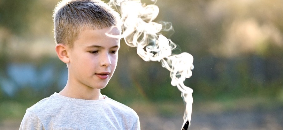 Boy looking at smouldering stick