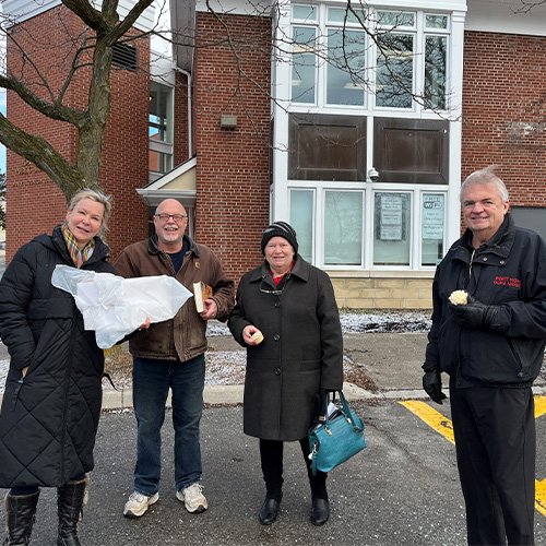 Four people standing beside a building 