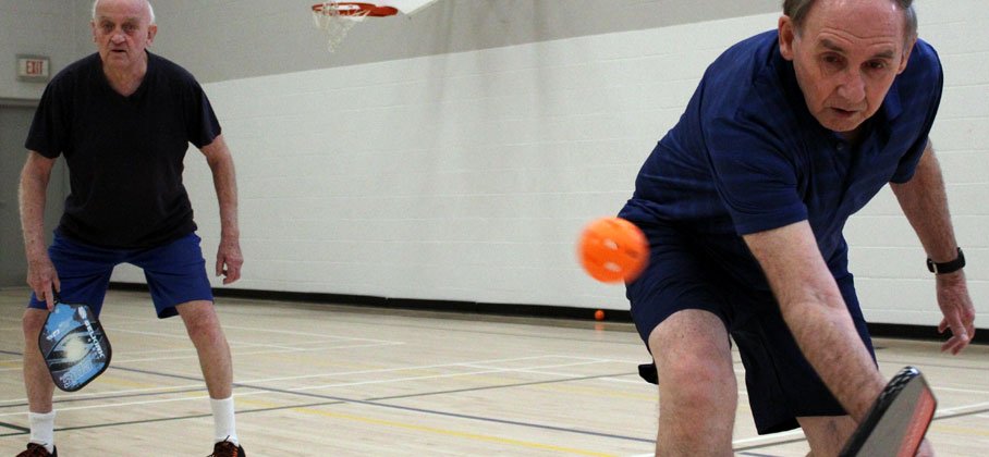 a picture of 2 seniors playing pickleball