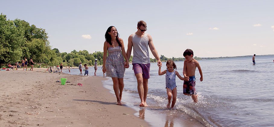 family holding hands walking along a sandy beach on a summer day