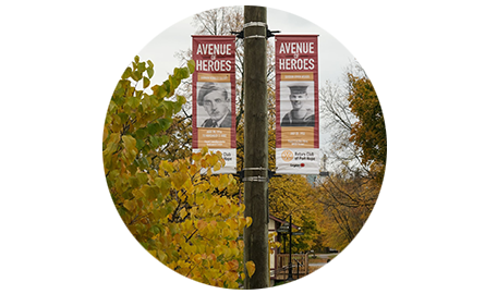 Two posters on a lamp post featuring images of veterans