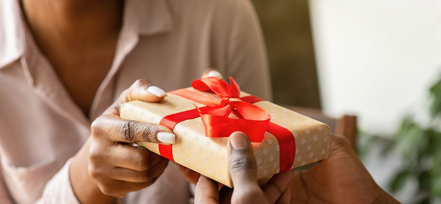 A person passing a gift box over to another 