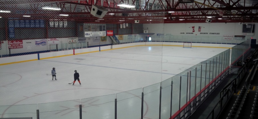 two children in hockey equipment on an indoor ice rink