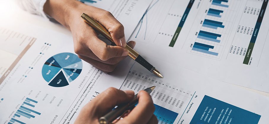 a person writing with pen on a pie chart