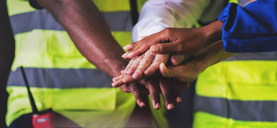 Image of workers with their hands in a circle 